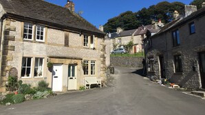 A narrow street lined with stone buildings, some with visible windows and doors, and a few with satellite dishes. - The Old Vicarage B&B (Buxton)