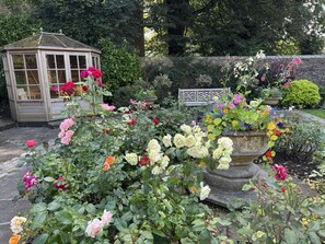 A garden with a variety of flowers, a gazebo, and a stone wall. - The Old Vicarage B&B (Buxton)