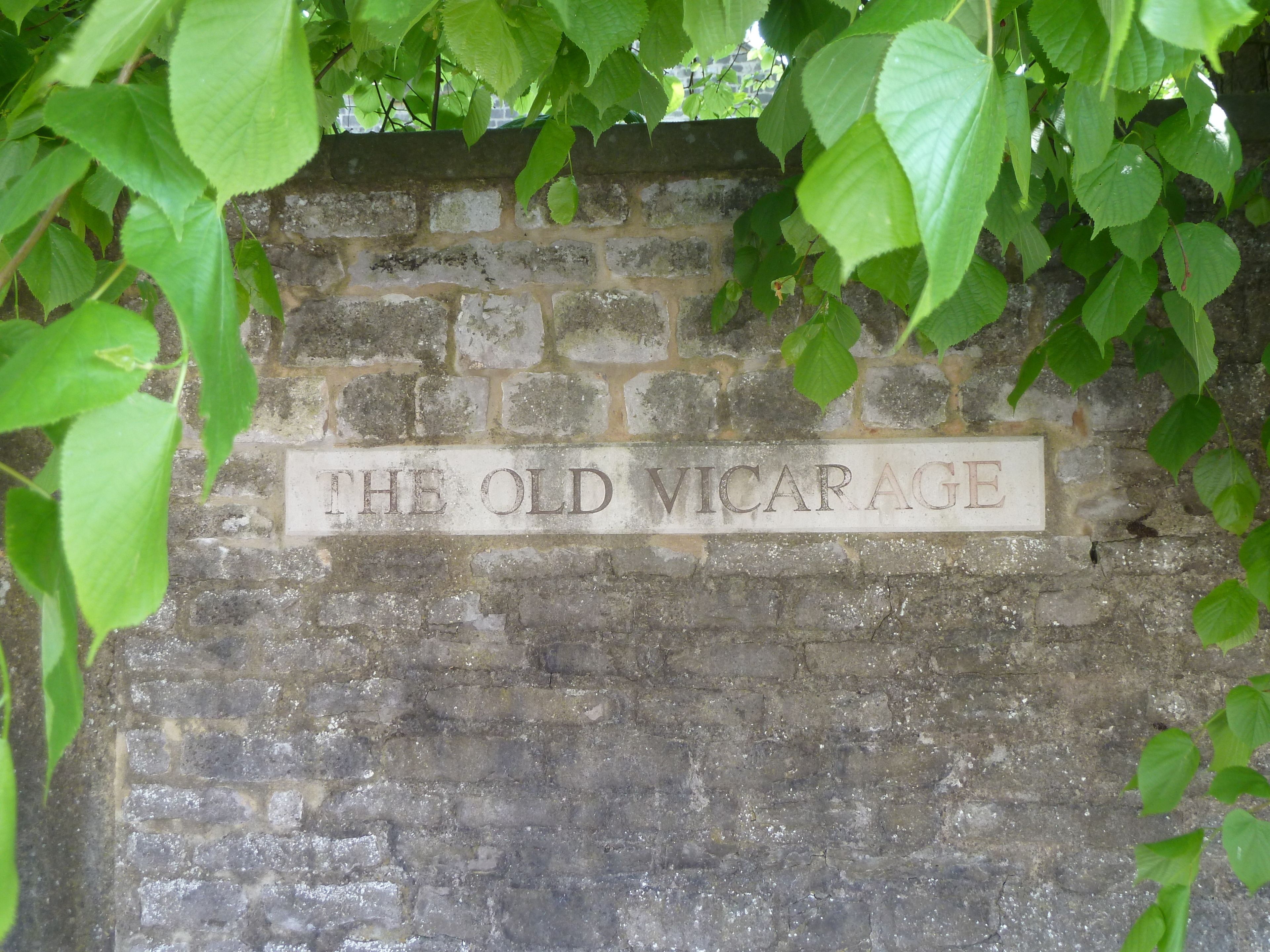 A stone wall with a sign that reads "THE OLD VICARAGE".