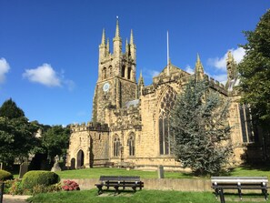 A historic church with a tall tower and Gothic architecture, surrounded by a well-maintained lawn and benches. - The Old Vicarage B&B (Buxton)