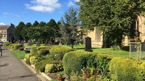 A cemetery with well-maintained hedges, a stone monument, and a building in the background. - The Old Vicarage B&B (Buxton)
