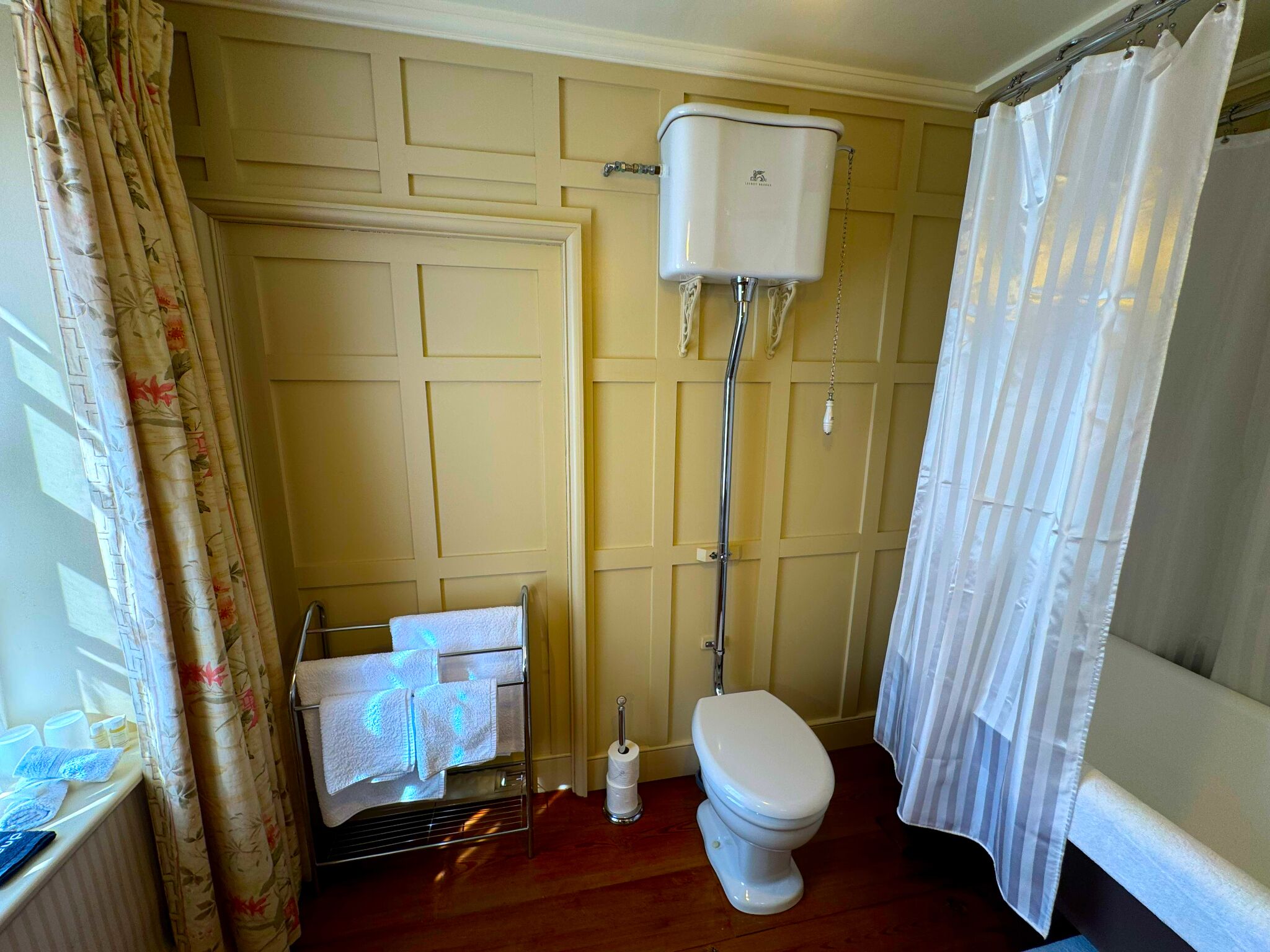 Un baño con inodoro, toallero y soporte para papel higiénico.