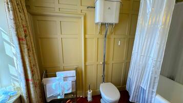 Un baño con inodoro, toallero y soporte para papel higiénico.