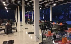 An indoor dining area with tables and chairs, large pillars, and a ceiling with exposed beams.