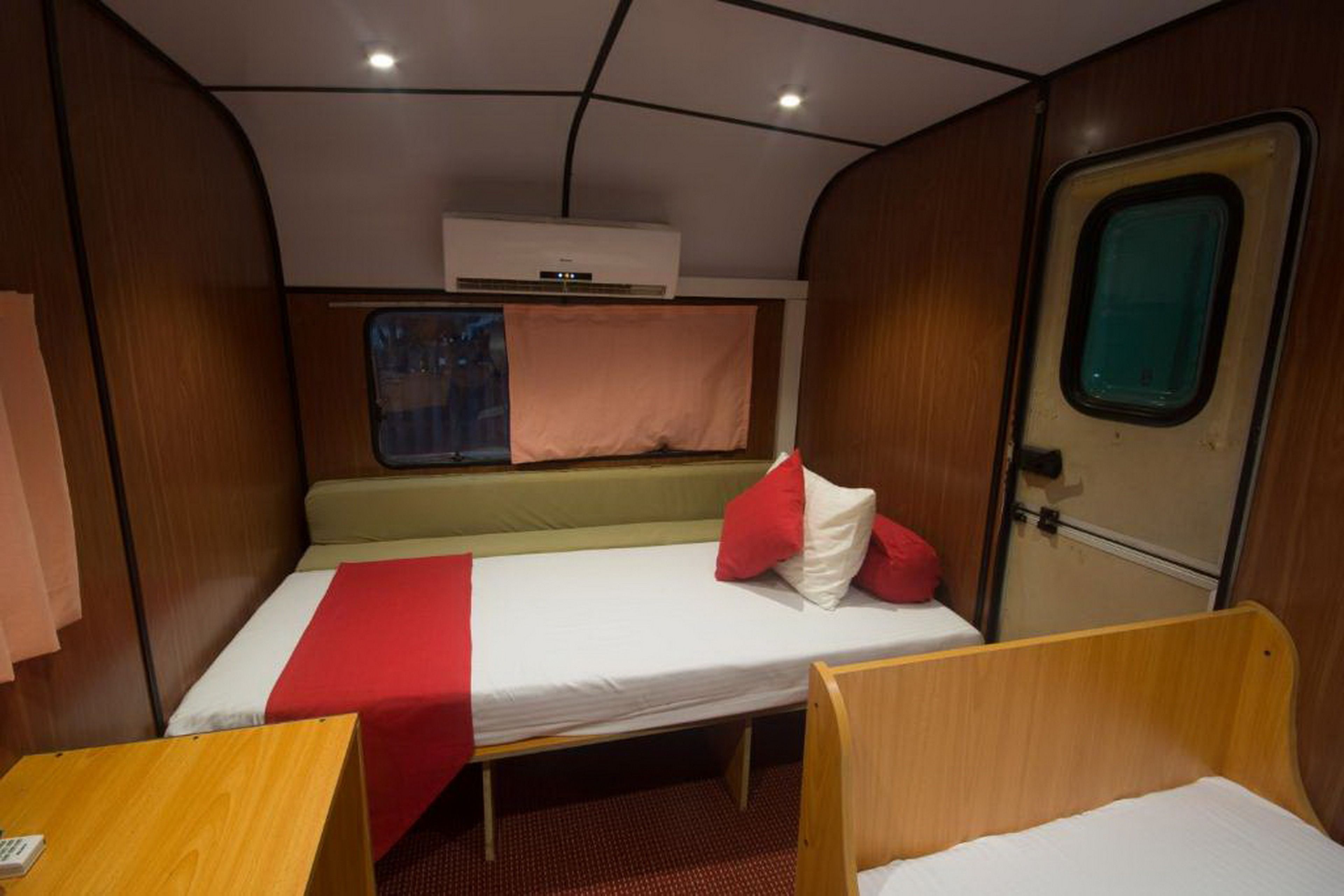 A compact cabin with a single bed, a small table, and a window.