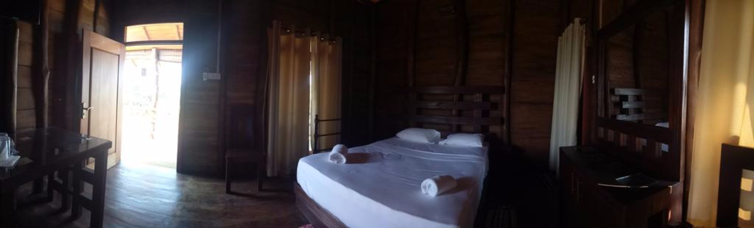 A wooden room with a bed, a desk, and a chair.