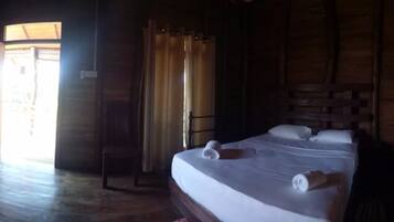 A wooden room with a bed, a desk, and a chair.