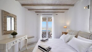 A bedroom with a bed, bedside tables, a desk, a mirror, and a view of the outdoors. - Nalu Villa Mykonos (Mykonos)