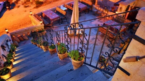 Una escalera con plantas en macetas, asientos exteriores y una barandilla.