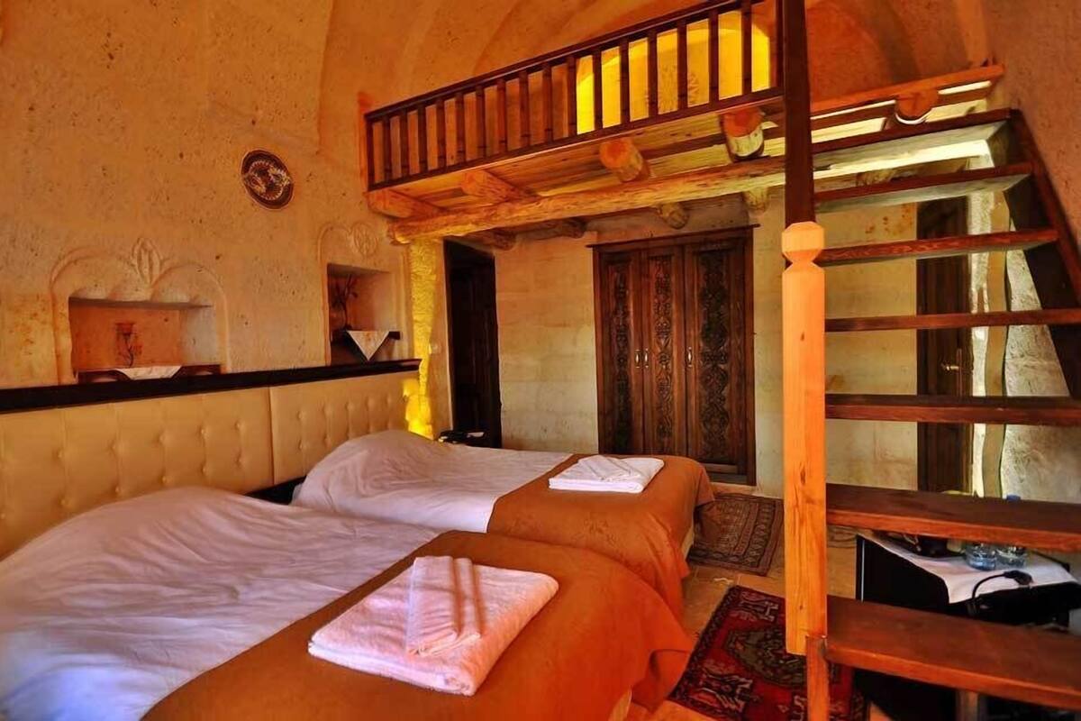 A room with two beds, a wooden staircase, and a small table with a lamp.