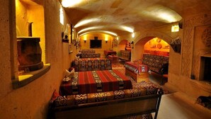Un interior acogedor con poca luz, techo abovedado alto, sofás estampados y chimenea.