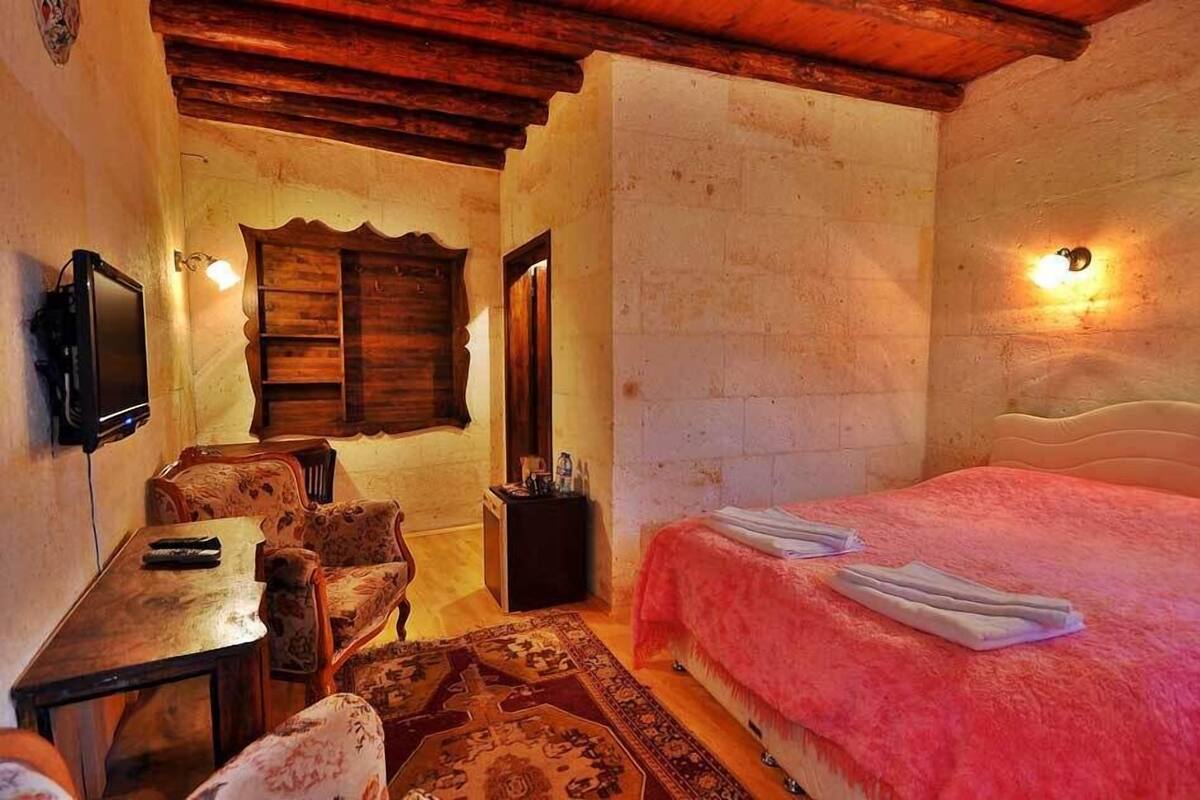 A cozy room with a bed, a small table, a chair, and a TV.