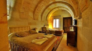 Un dormitorio con una cama grande, un aparador de madera y un techo abovedado.