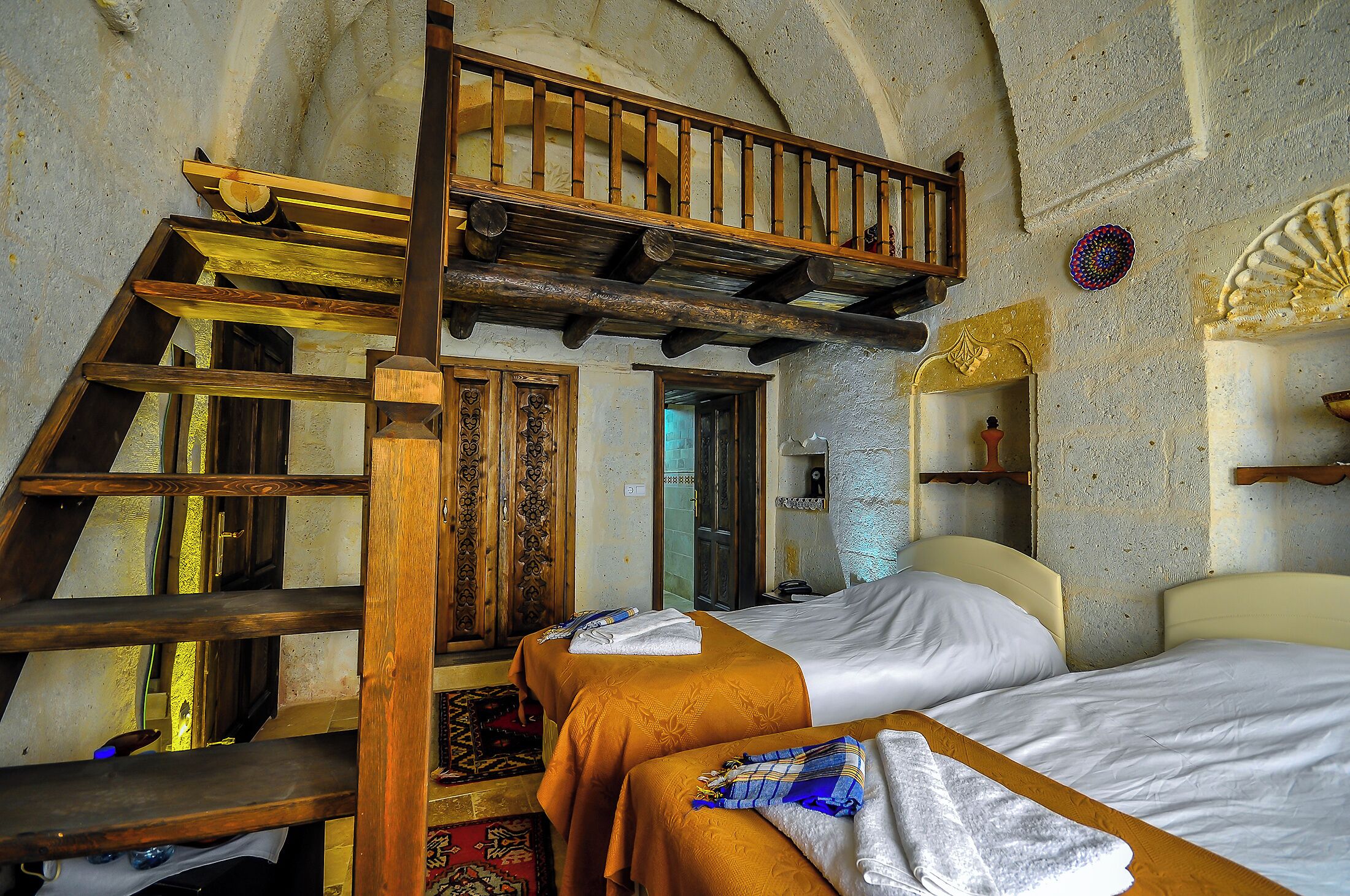 Ein Zimmer mit zwei Betten, einer Holztreppe und einem kleinen Balkon.