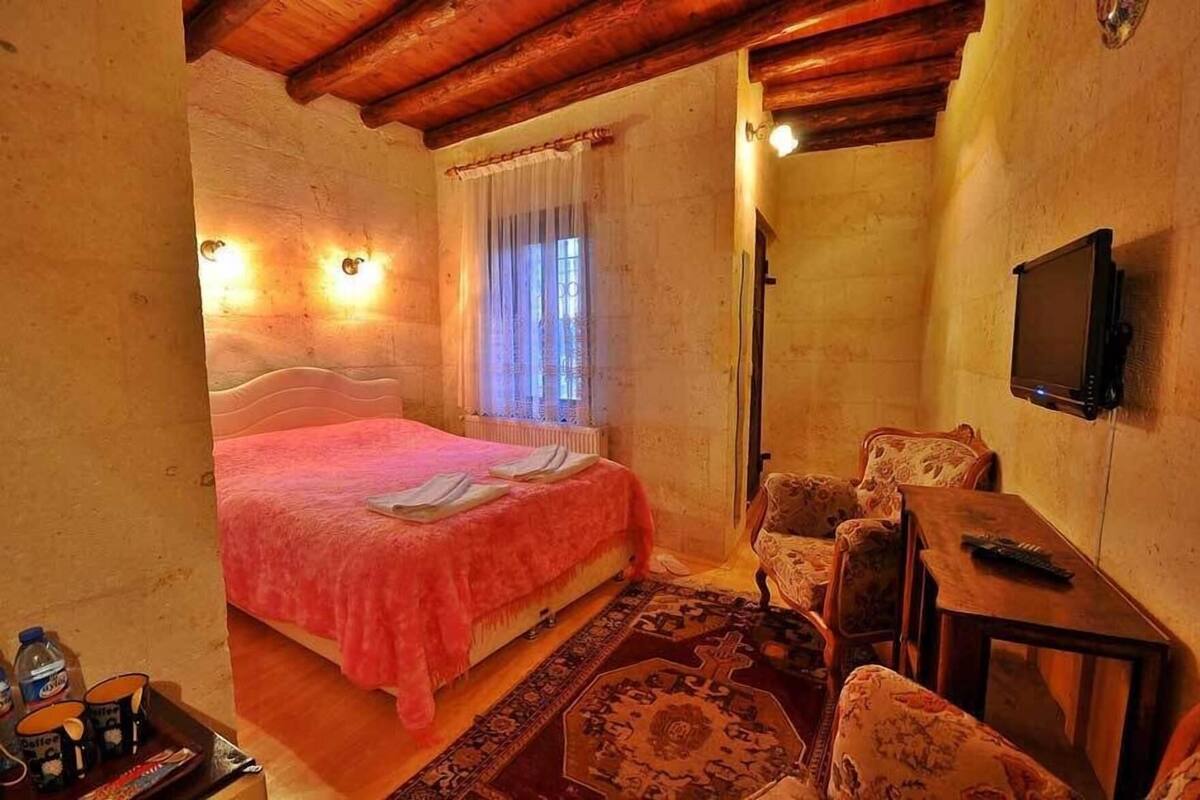 A bedroom with a bed, a chair, a TV, and a small table.