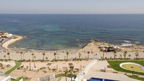 A beach resort with a curved shoreline, palm trees, and a pool area. - Sea Senses Apartments - Marholidays (Torrevieja)