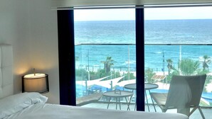 A hotel room with a bed, a nightstand, a lamp, and a large window overlooking the ocean. - Sea Senses Apartments - Marholidays (Torrevieja)
