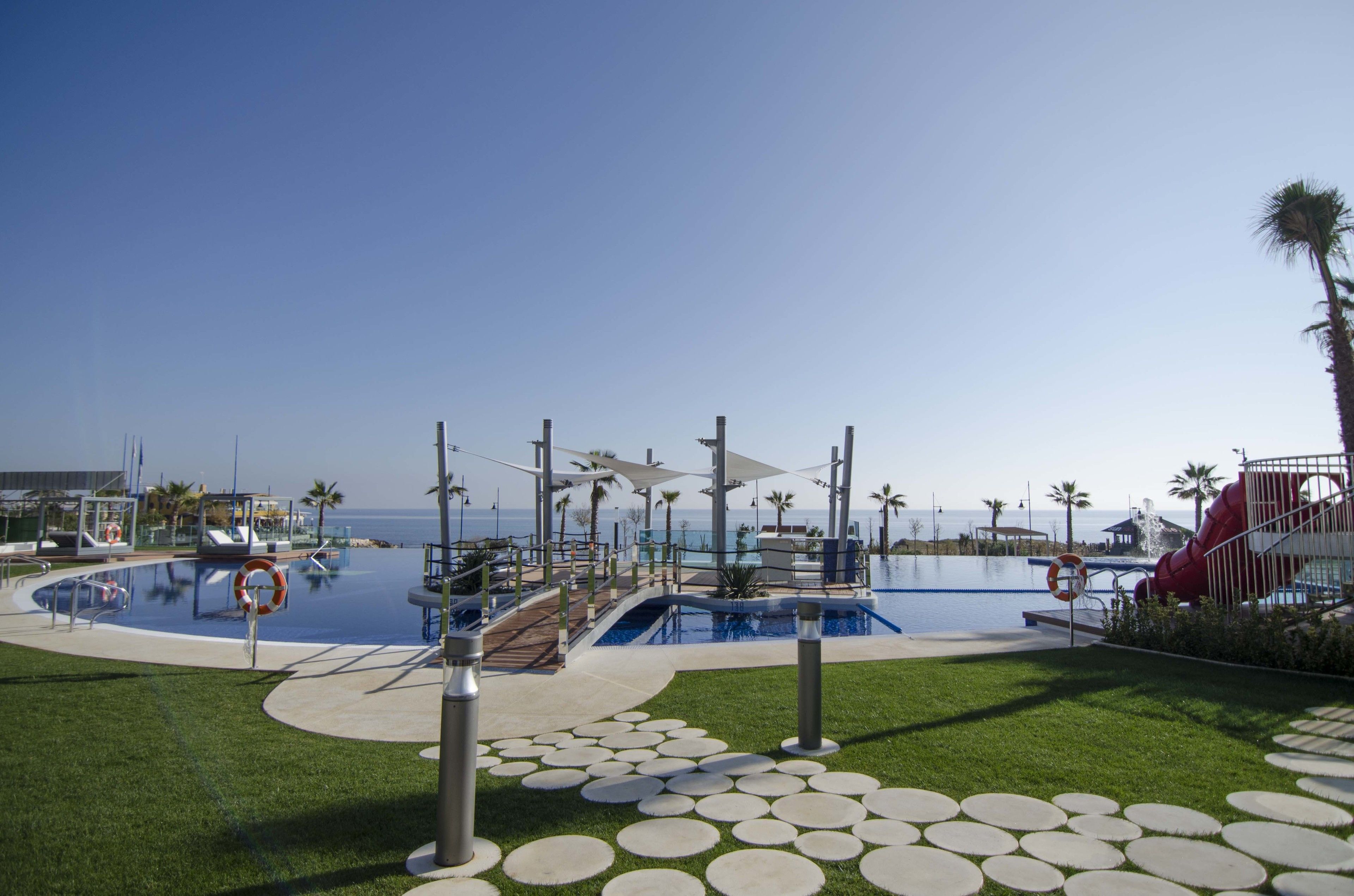 A resort pool area with a circular pool, palm trees, and a lifeguard stand.