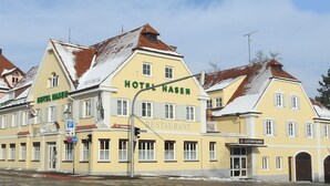 A yellow building with "HOTEL HASEN" and "RESTAURANT" signs, featuring a traditional European architectural style with multiple windows and a sloped roof.