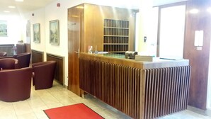 A reception area with a wooden reception desk, seating area, and framed pictures on the wall.