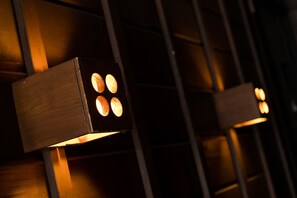 A close-up of a modern light fixture with four illuminated bulbs, mounted on a wooden structure. - A1 Niseko (Kutchan)