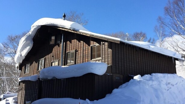 A wooden cabin with a sloped roof covered in snow, surrounded by a snowbank. - A1 Niseko (Kutchan)