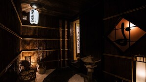 A traditional Japanese interior with wooden walls, a stone lantern, and a sign with Japanese characters. - A1 Niseko (Kutchan)