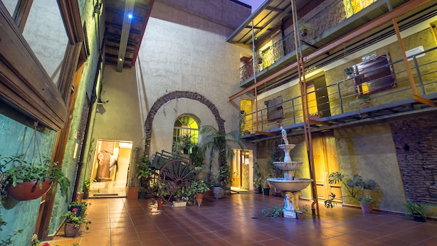 Un patio interior con una fuente, plantas en macetas y una pared de piedra rústica.