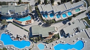 Vue aérienne d’un complexe hôtelier doté de plusieurs piscines, de chaises longues et d’un aménagement paysager bien entretenu.