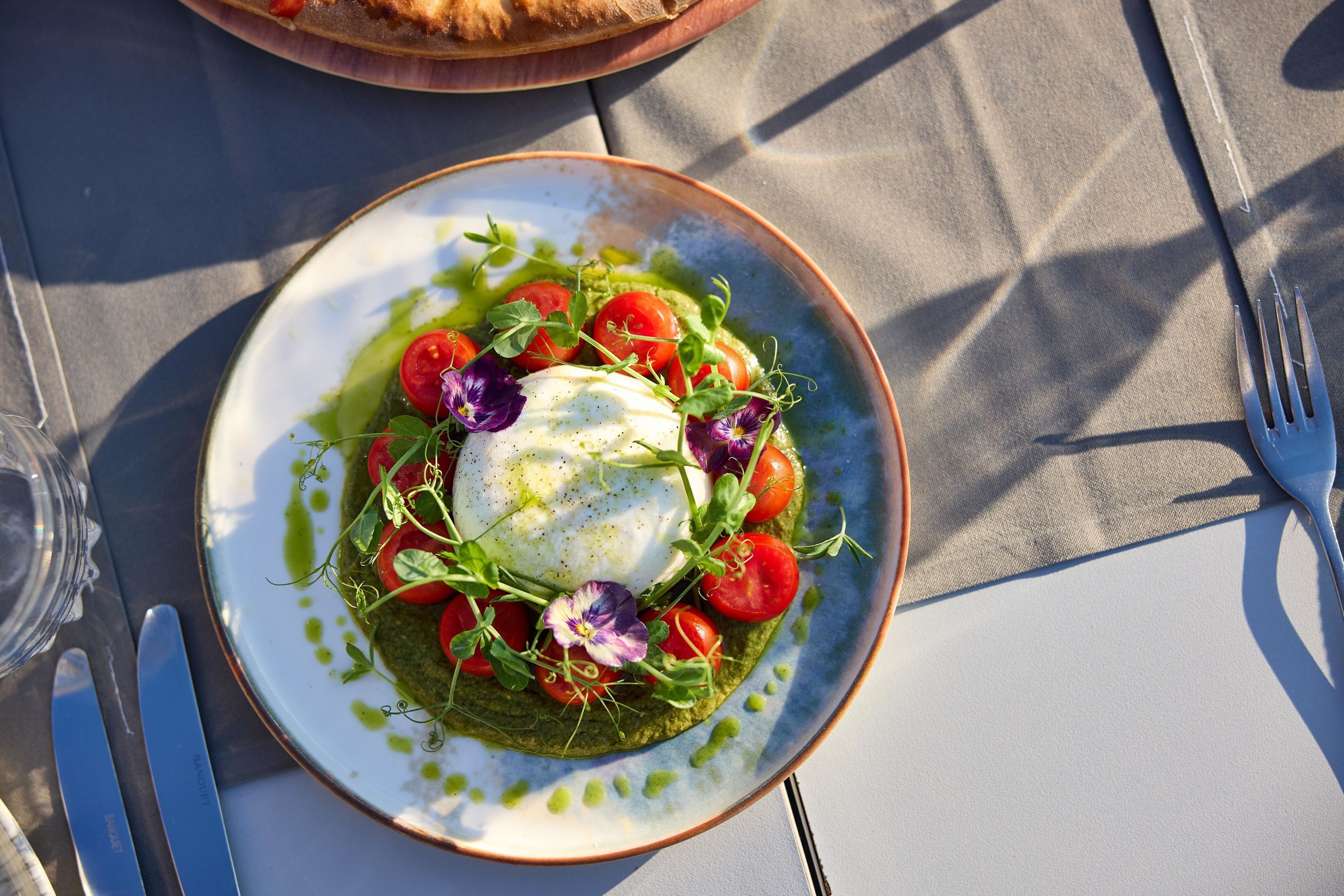 A plate of food with a poached egg, tomatoes, and greens on a table.