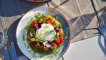 A plate of food with a poached egg, tomatoes, and greens on a table.