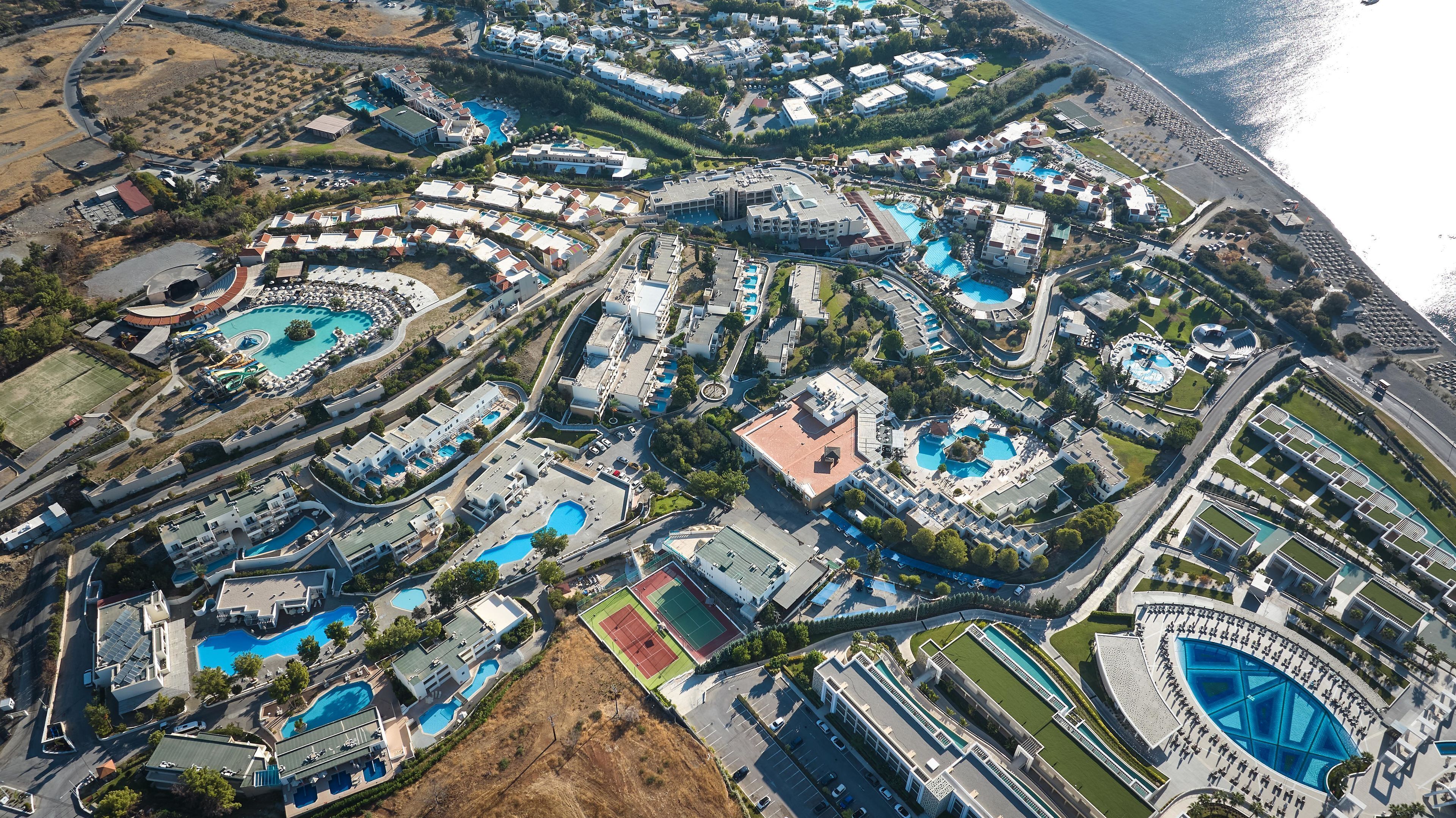 An aerial view of a resort with multiple swimming pools, a beach, and a large hotel complex.