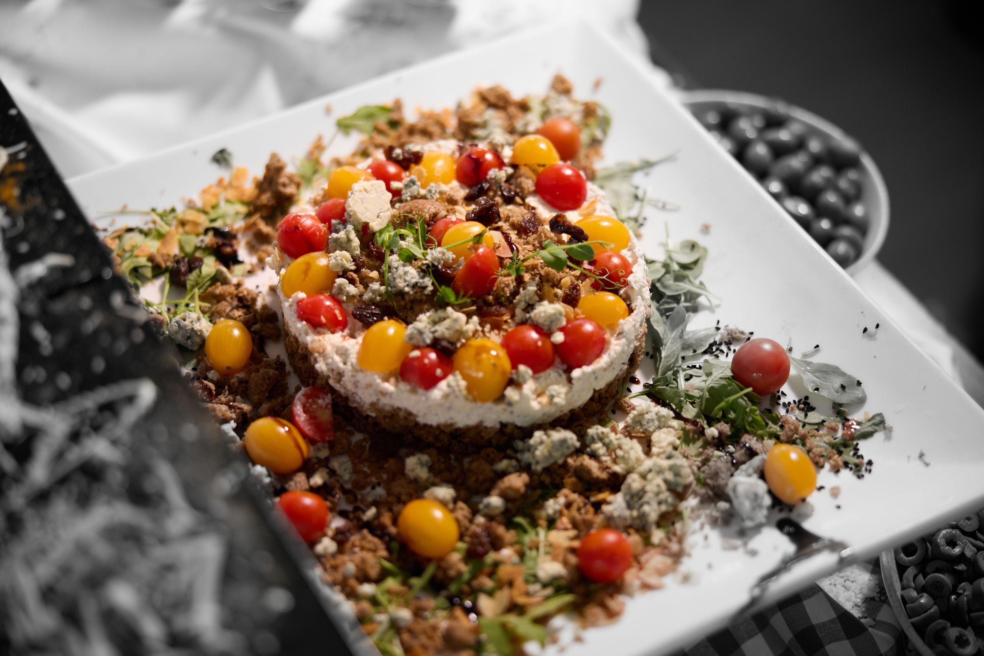 Un postre con una variedad de ingredientes, incluyendo cerezas, nueces y hojas verdes, sobre un plato blanco.