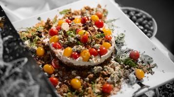 Un postre con una variedad de ingredientes, incluyendo cerezas, nueces y hojas verdes, sobre un plato blanco.