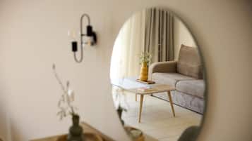A living room with a sofa, a coffee table, and a mirror reflecting the room.
