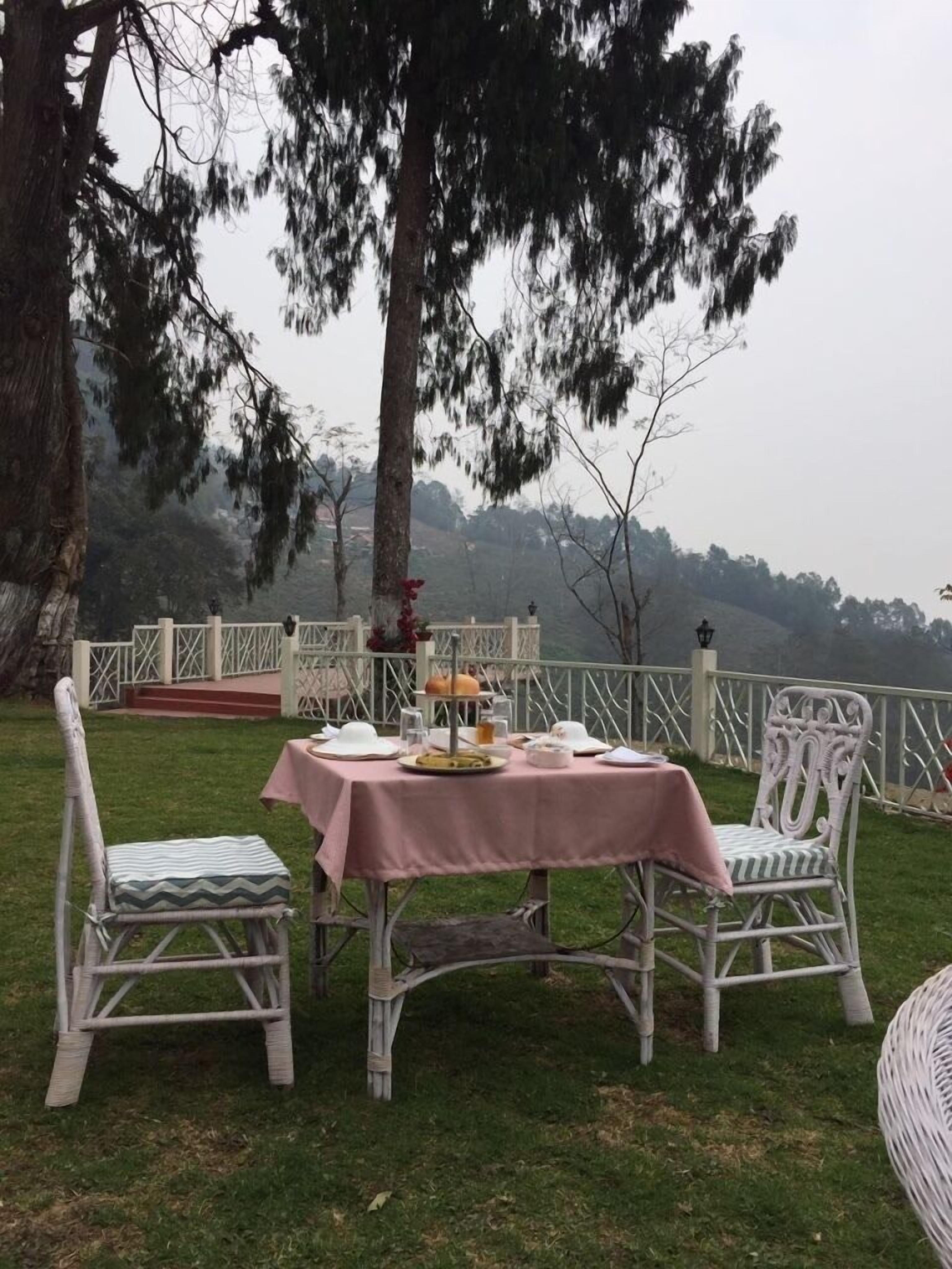 An outdoor dining area with a table set for two, surrounded by wicker chairs.