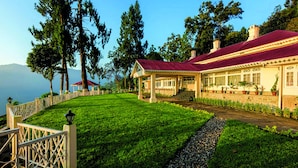 A hotel with a red roof, a covered patio, and a view of the sea. - Ging Tea House (Darjeeling)
