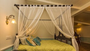 A four-poster canopy bed with a green quilt, two bedside tables, and a wall-mounted light fixture. - Ging Tea House (Darjeeling)