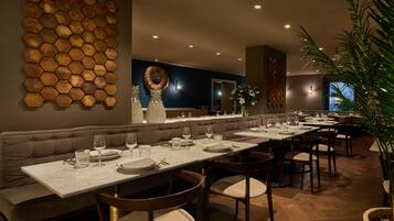 Een restaurant met een lange balie, meerdere tafels en diverse zitmogelijkheden, zoals zitjes en stoelen.