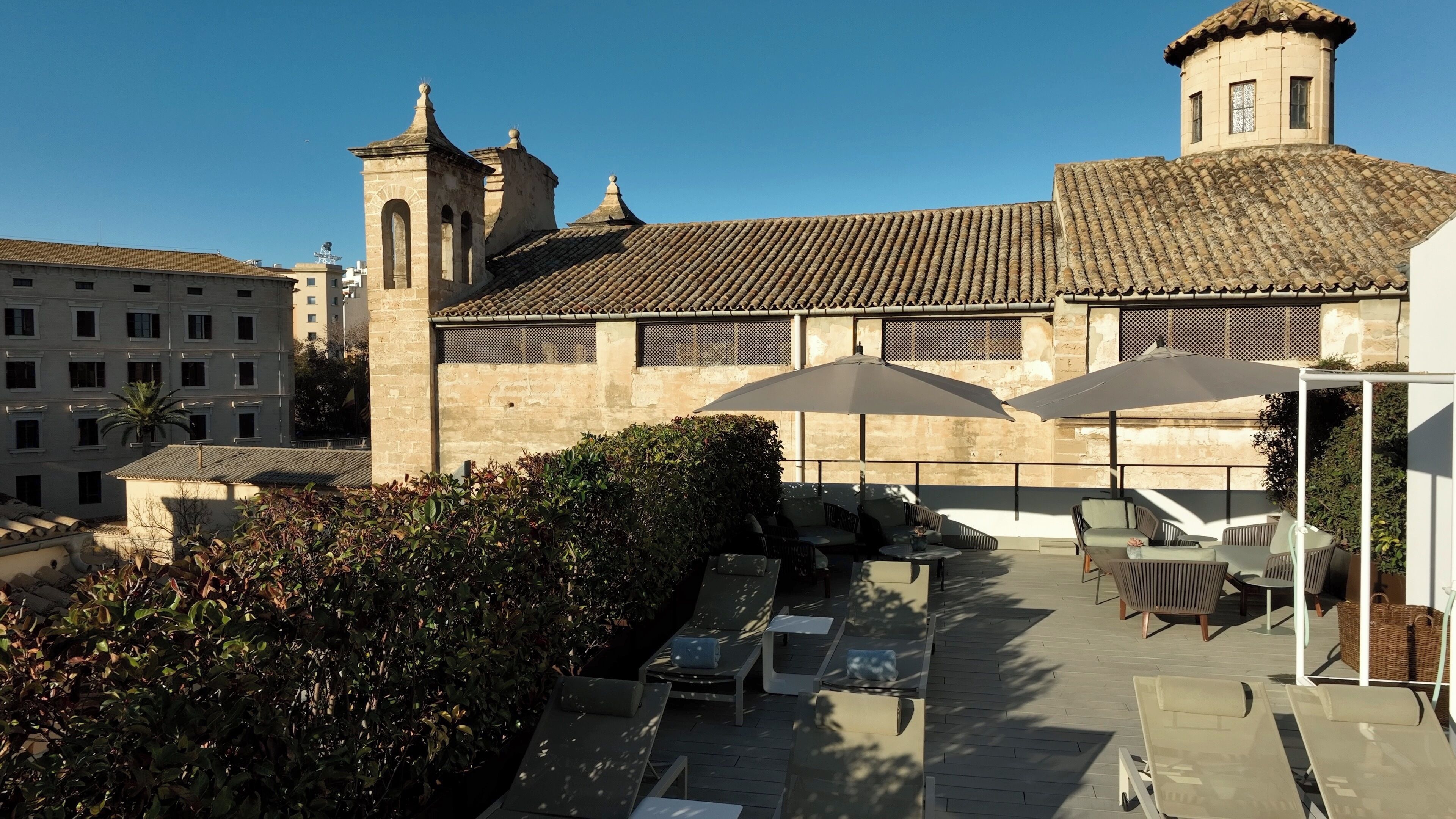 Un patio con mesas al aire libre y un edificio de piedra con tejado de tejas.