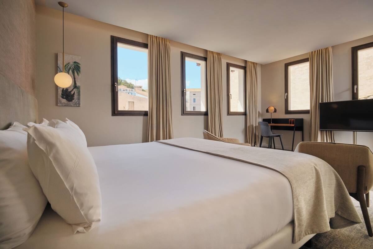 Una habitación de hotel con una cama grande, un escritorio, una silla y un televisor.