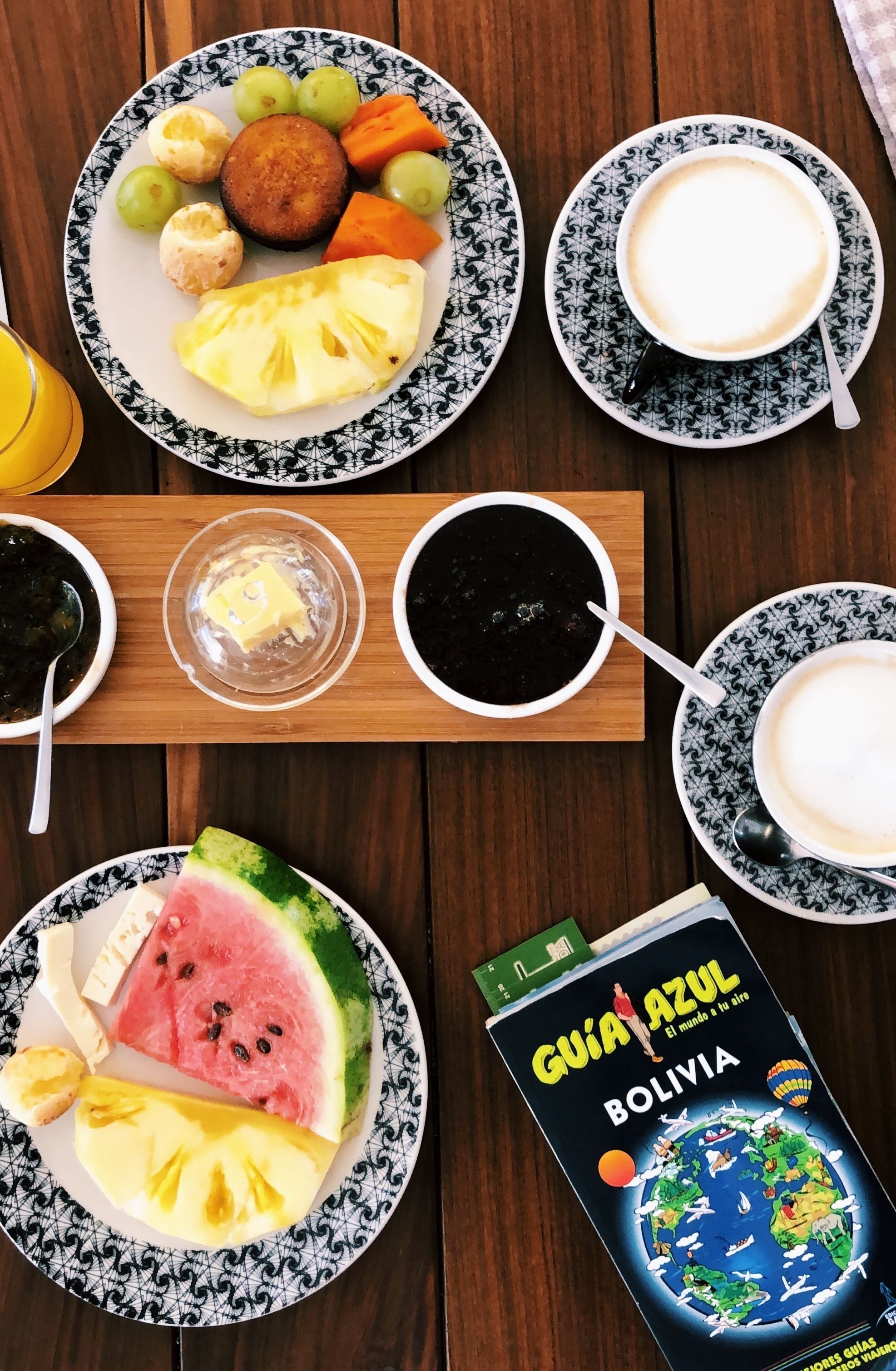 Una mesa con platos de comida, tazas de café y un libro guía de viajes.