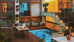 A multi-level indoor space with a pool, wooden flooring, and potted plants. - Cosmopolitano Hotel Boutique (Santa Cruz)