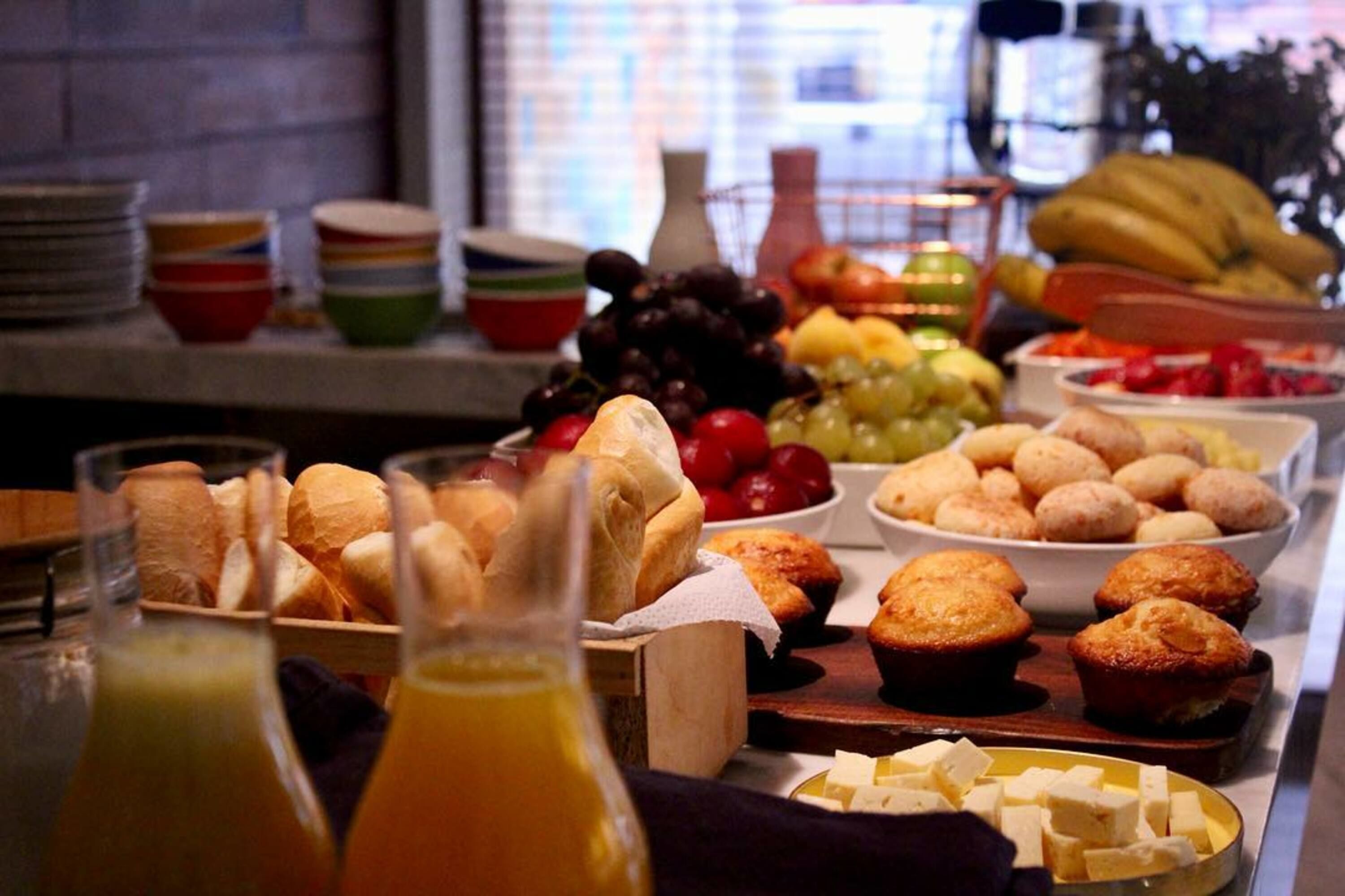 Een buffet met diverse etenswaren, zoals brood, muffins, fruit en kaas.