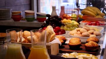Een buffet met diverse etenswaren, zoals brood, muffins, fruit en kaas.