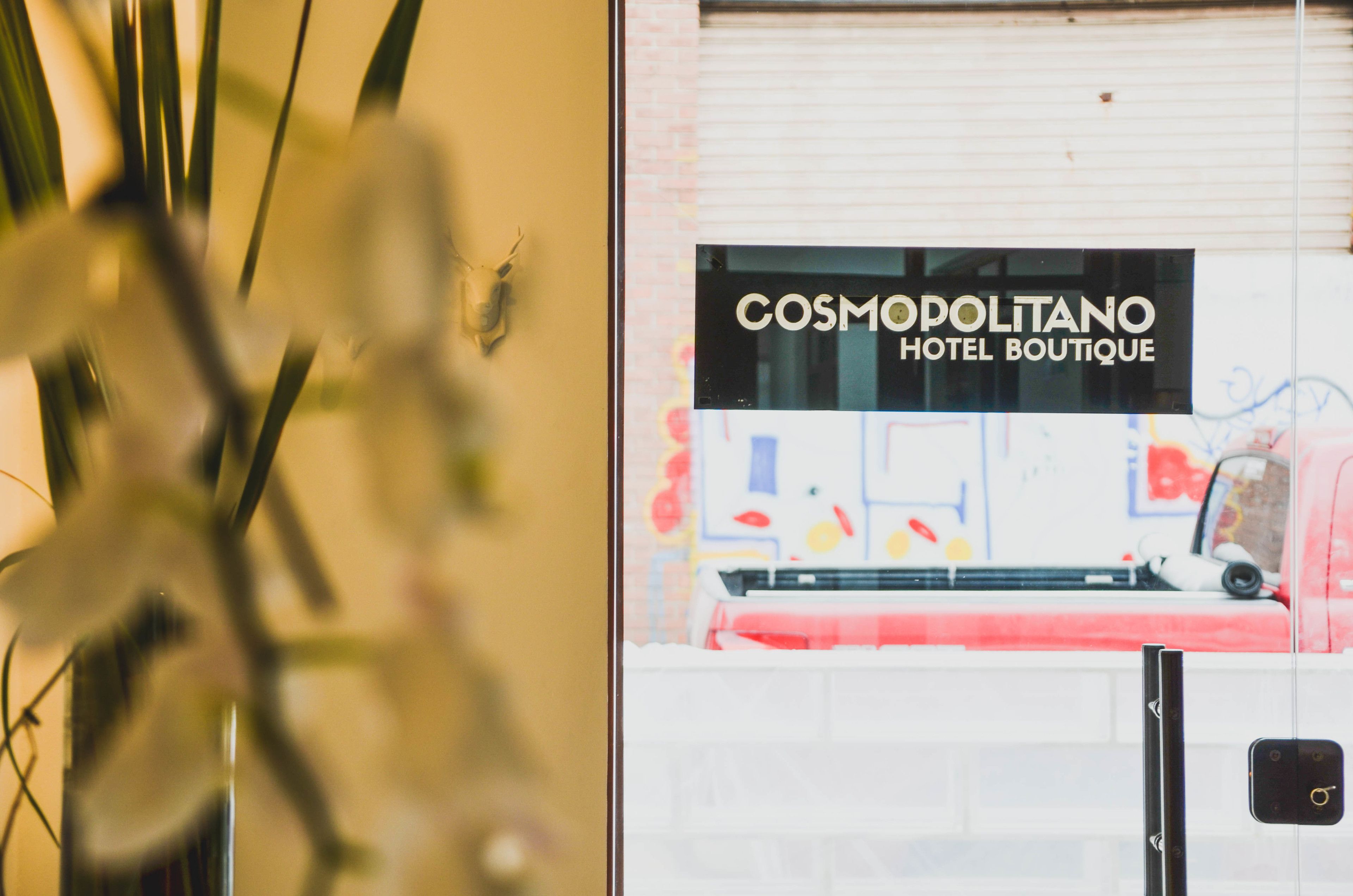 Schild für das Hotel 'COSMODOLITANO HOTEL BOUTIQUE' mit modernem Design und Blick ins Innere.