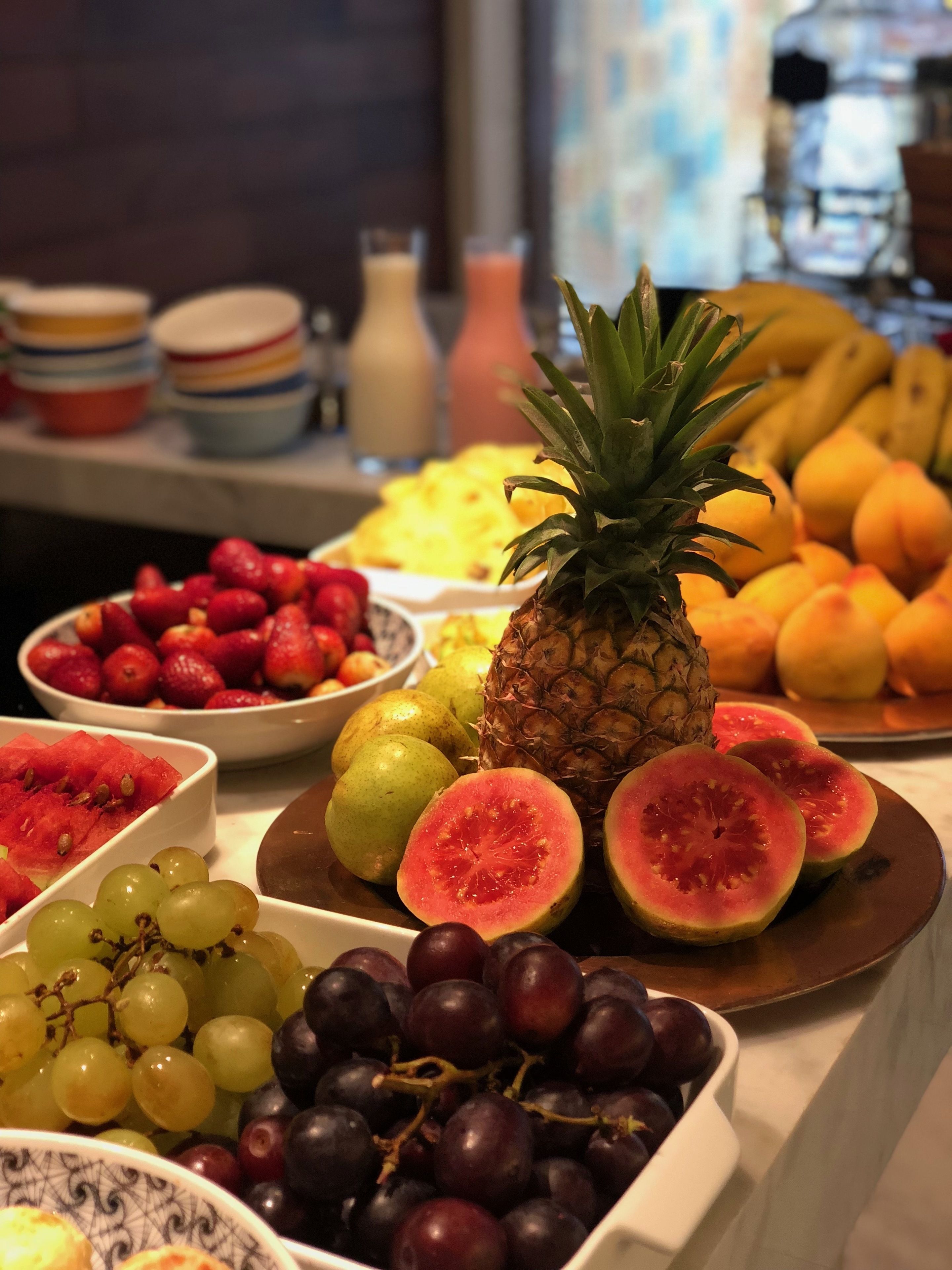 A buffet table with various fruits including grapes, watermelon, and pineapple.