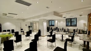 A spacious conference room with multiple tables and chairs, white walls, and a large window providing natural light. - Chillout Hostel Zagreb (Zagreb)