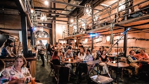 An indoor venue with tables and chairs arranged for dining or socializing, with people seated and some standing. - Chillout Hostel Zagreb (Zagreb)
