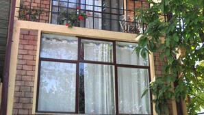 A two-story building with a brick facade, large windows with curtains, and a balcony with potted plants. - Family Cozy Bed & Breakfast (Addis Ababa)